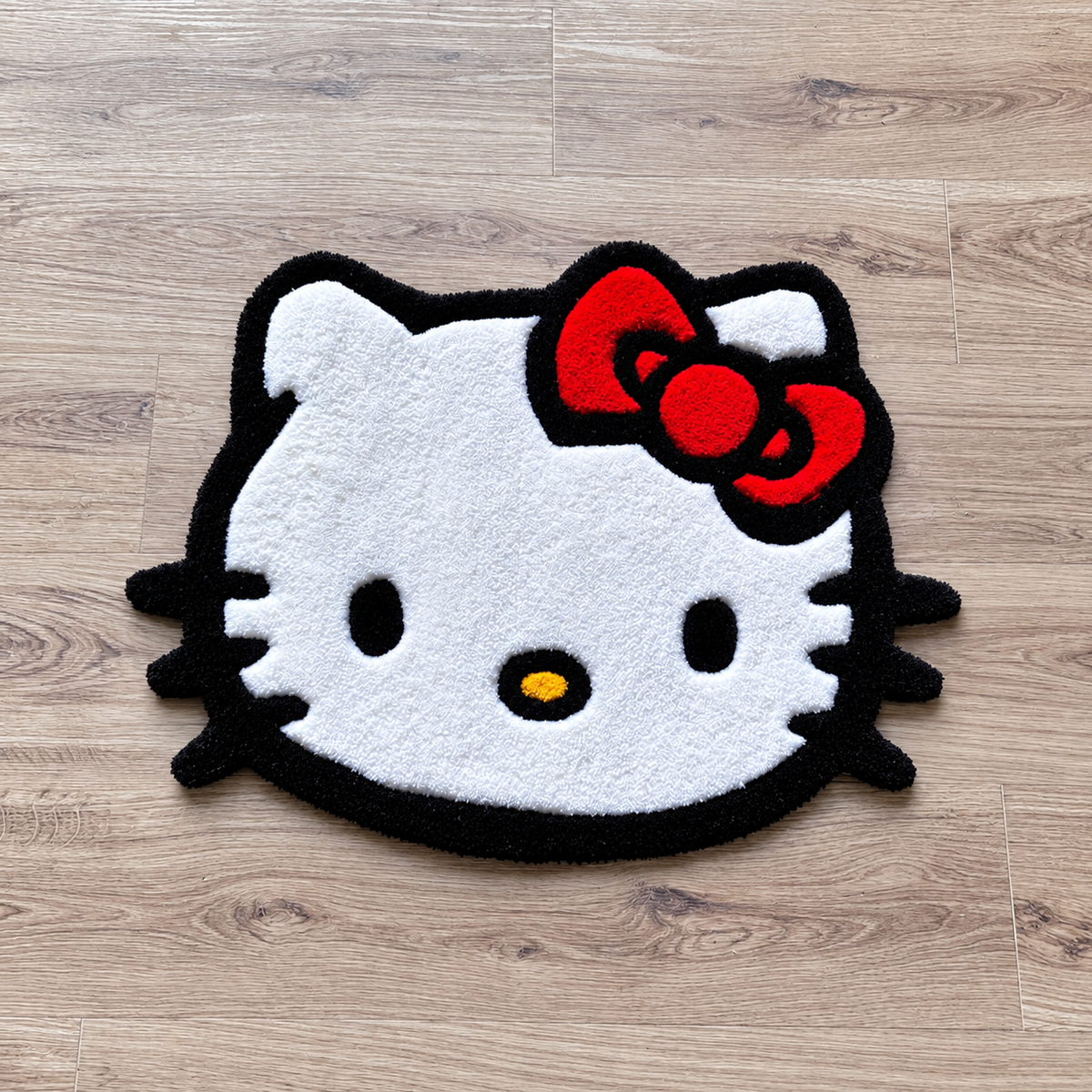 Hello Kitty Face rug on bright hardwood, close angled view, AI-edited product photo