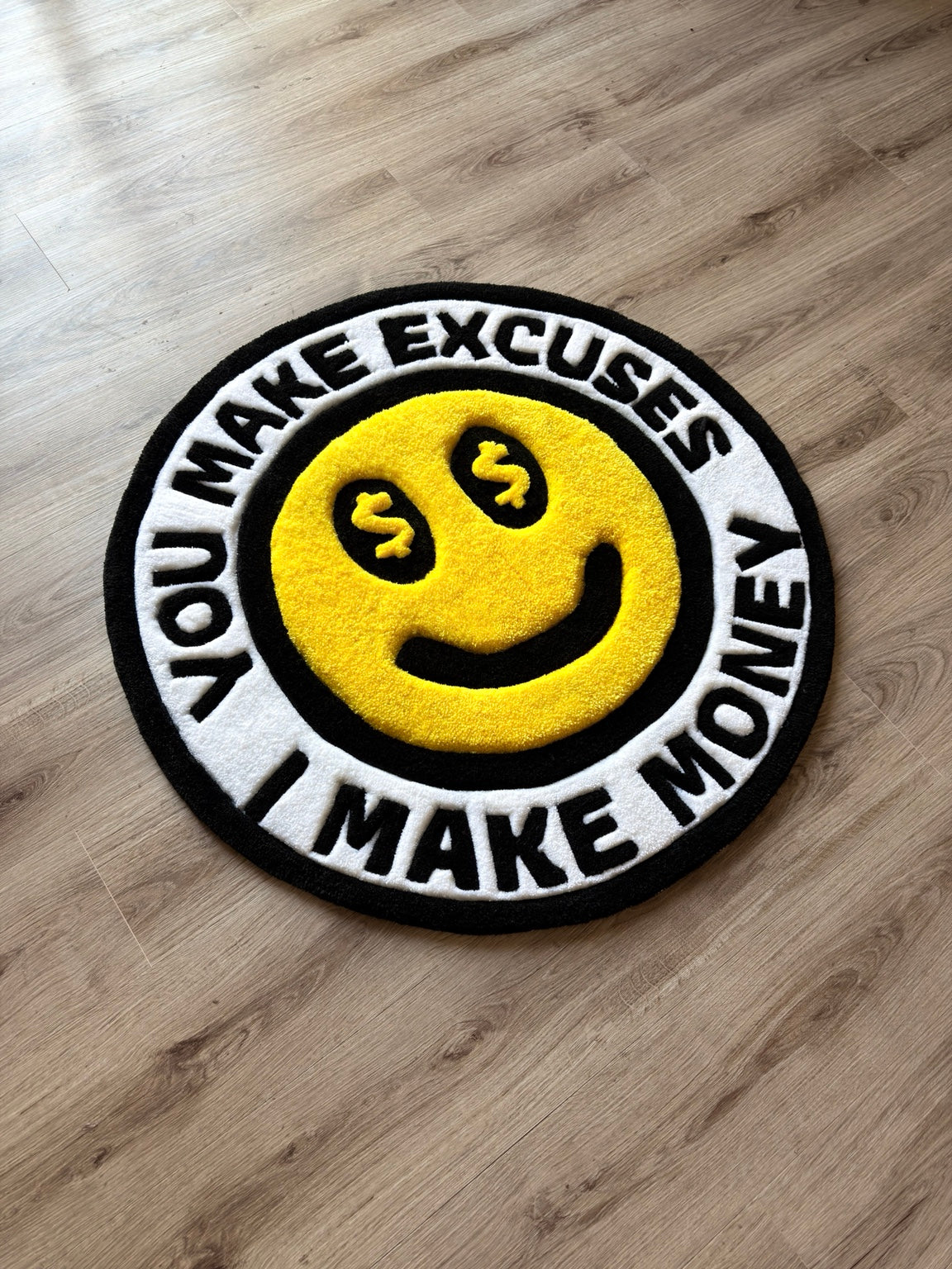 Round yellow money-eyes smiley rug with raised details and a black-and-white border reading You Make Excuses I Make Money.
