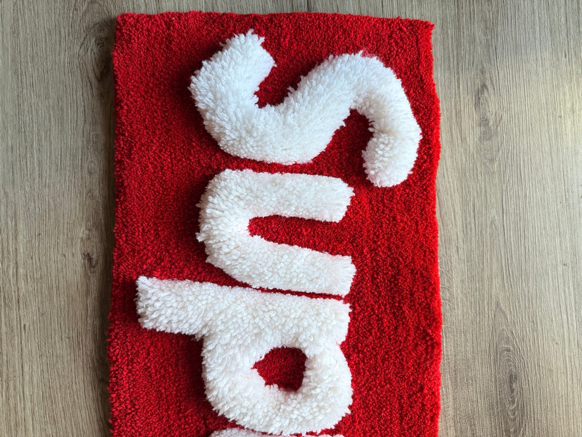 Close-up of the raised white tufted lettering and red rug texture